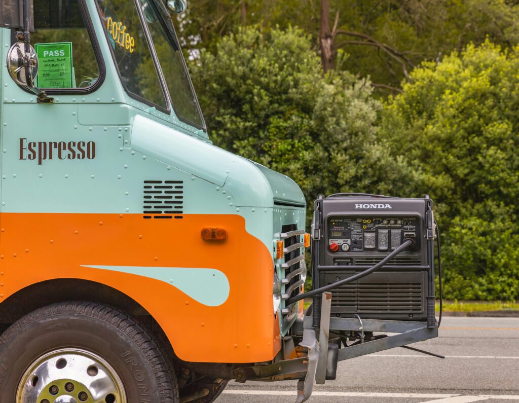 Close-up of a vibrant coffee truck with espresso branding and attached power generator on a sunny day.