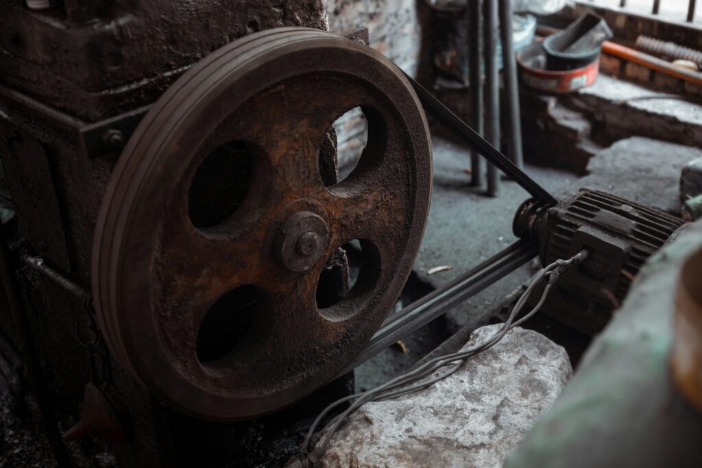 Close-up of a rusted industrial machine wheel in an old workshop setting.